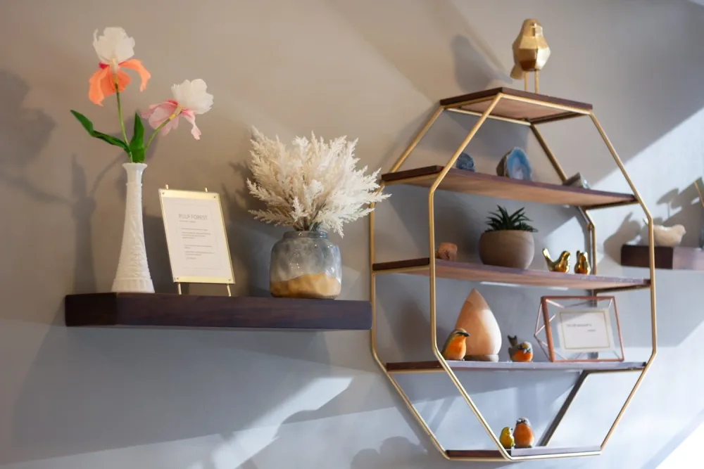 A styled shelf with flowers, plants, and candles inside Starling Salon